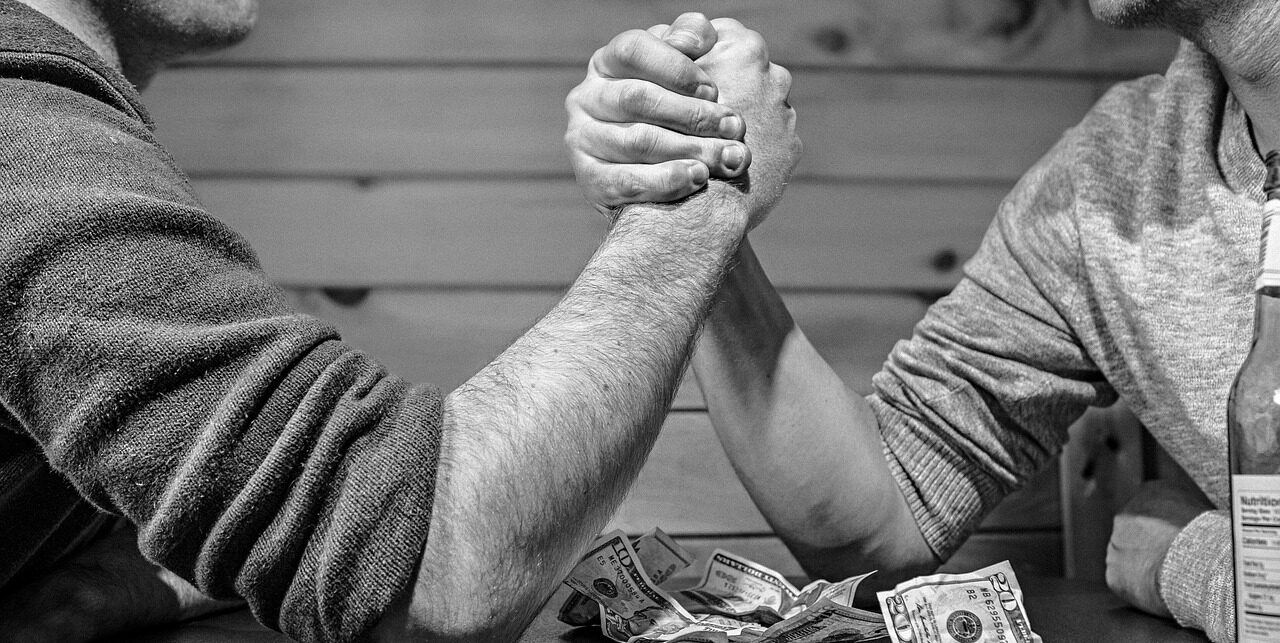 Arm Wrestling with cash on table in monochrome. Best variable annuities featured image.