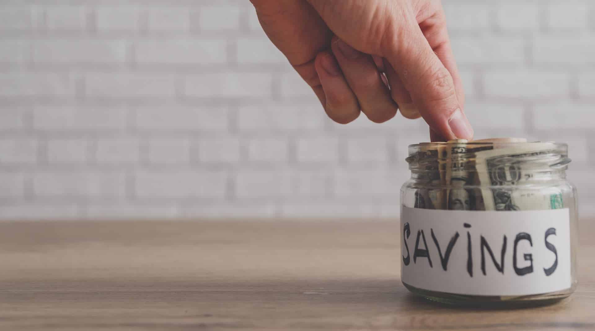 Man reaching into glass jar labeled savings